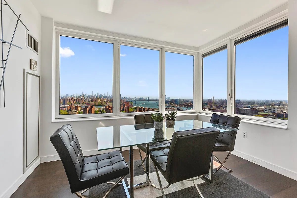 Thumbnail: Corner dining area with glass table and windows overlooking the Manhattan skyline, river and bridges