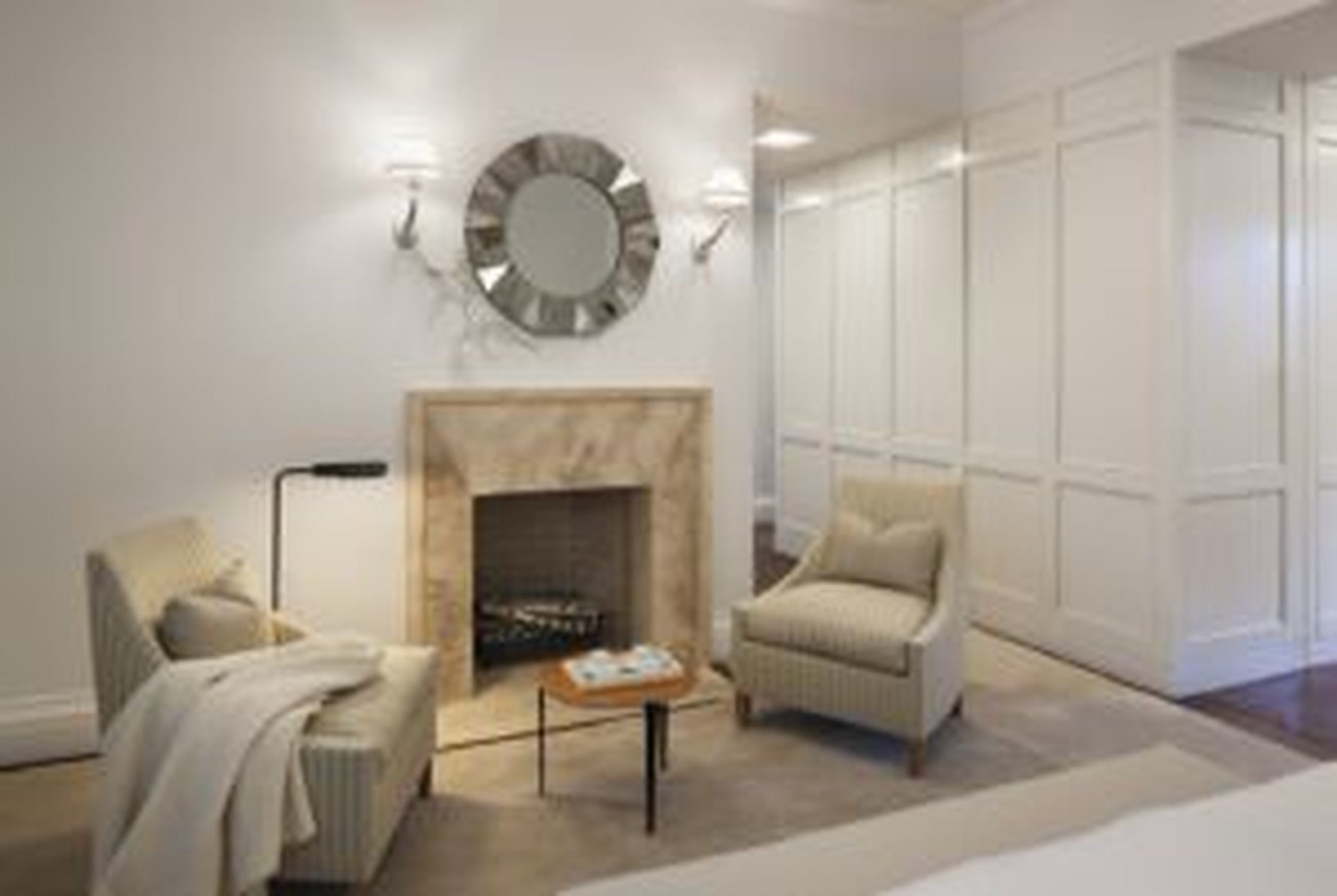 Thumbnail: Primary suite sitting room with stone fireplace, sunburst mirror and paired armchairs