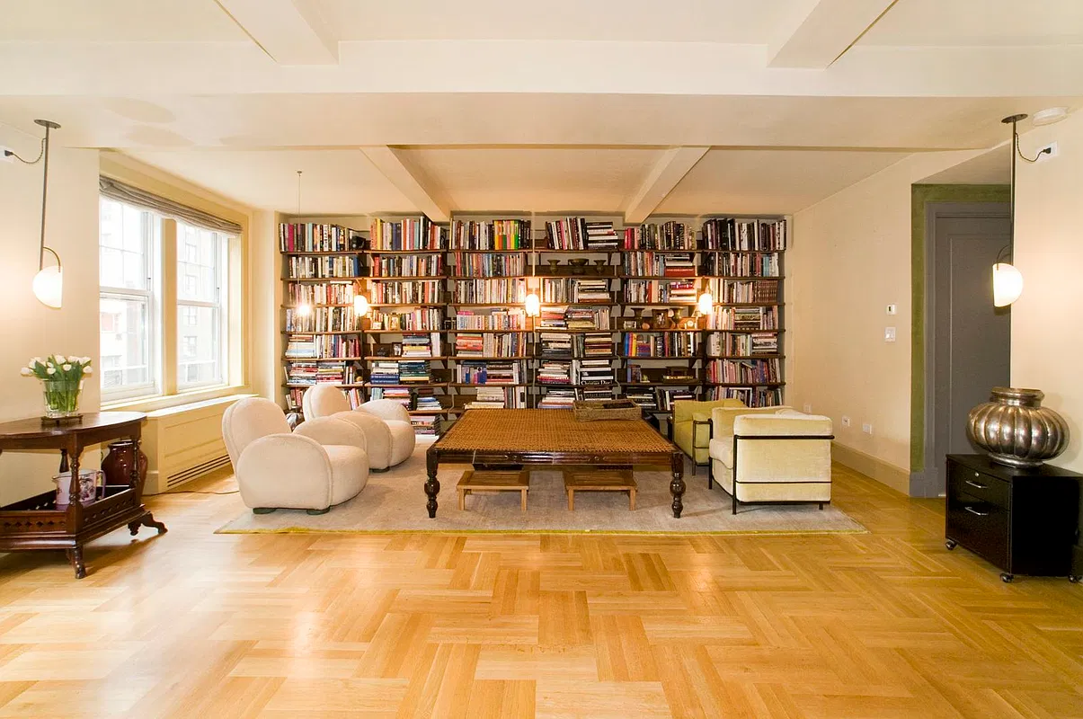 Living and dining area with wall of bookshelves, beamed ceiling and herringbone oak floors
