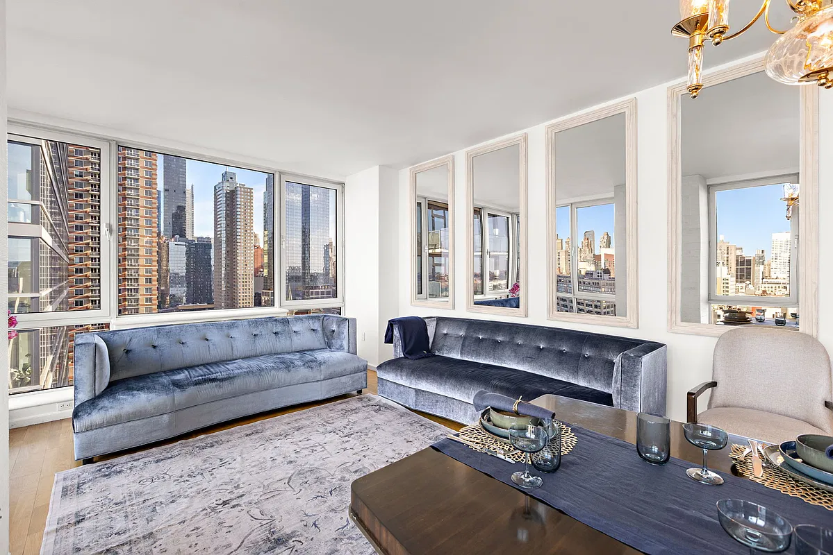 Thumbnail: Living room with two blue velvet sofas, tall mirrors and corner windows facing Manhattan towers