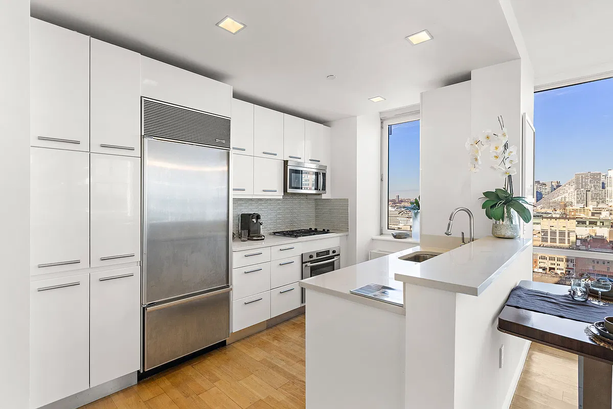 Thumbnail: White open kitchen with Sub-Zero refrigerator, stainless appliances and a window over the city