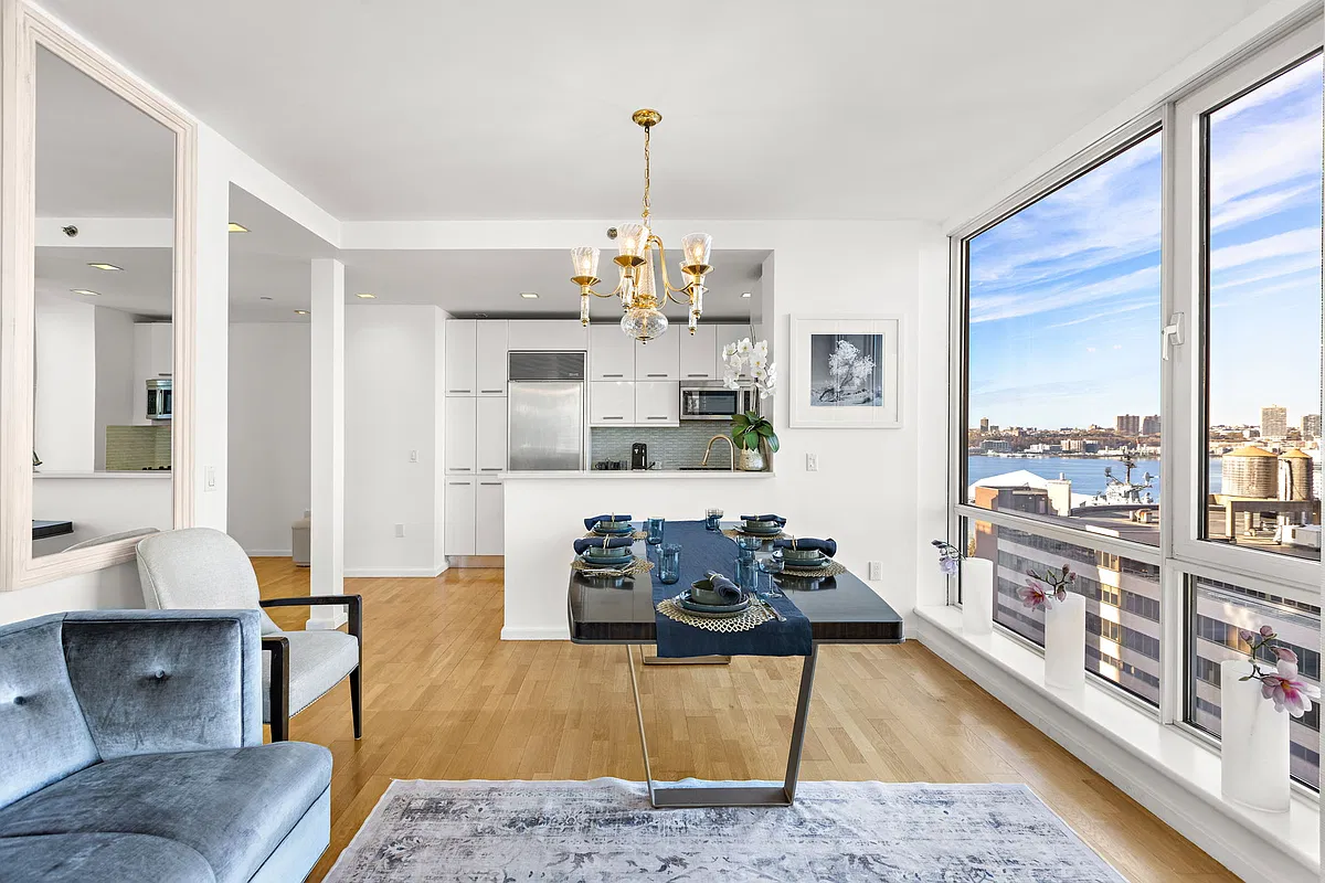 Thumbnail: Dining area with gold chandelier beside the open kitchen and a window view of the Hudson River